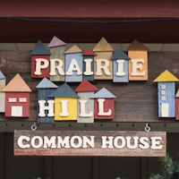 A home-made sign that spells out "Prairie Hill Common House" with little homes next to each other.